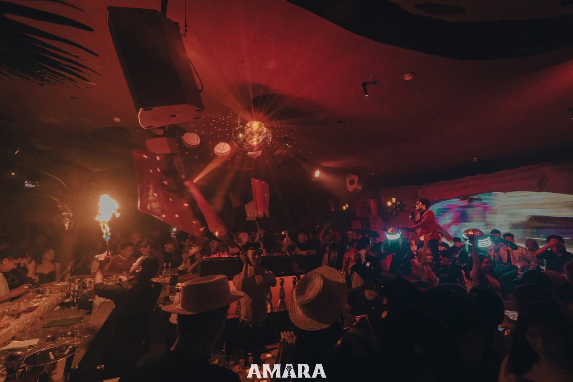 Không gian Amara Club về đêm với sân khấu, quả cầu disco và khách tham dự đông kín sàn.