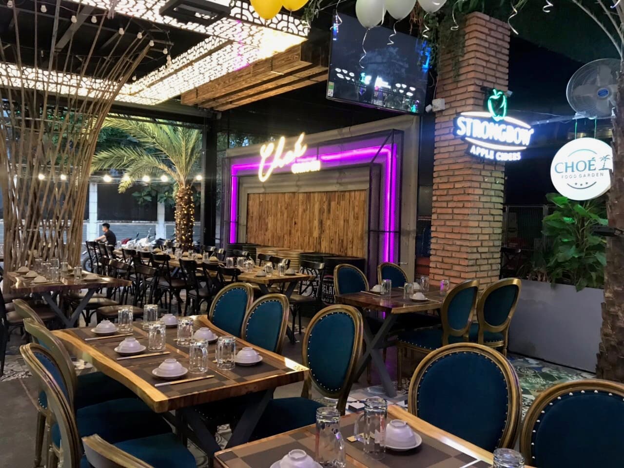 Không gian Chóe Food Garden về đêm với bảng hiệu neon Chóe và khu bàn tiệc