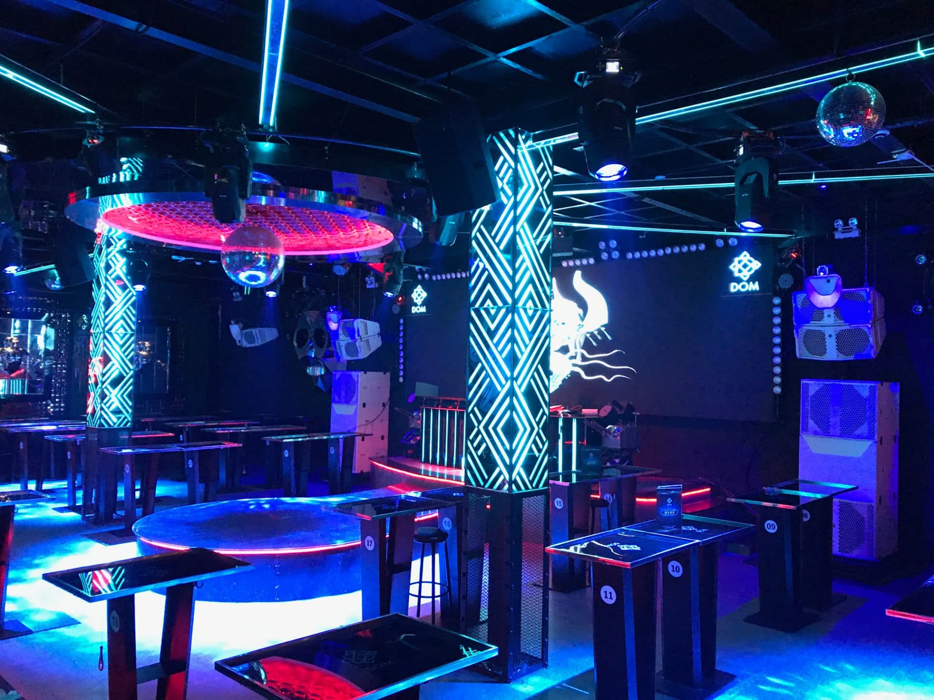 Toàn cảnh Main Floor Dom Club với logo thương hiệu DOM, hai quả cầu disco và dàn bàn VIP đánh số.
