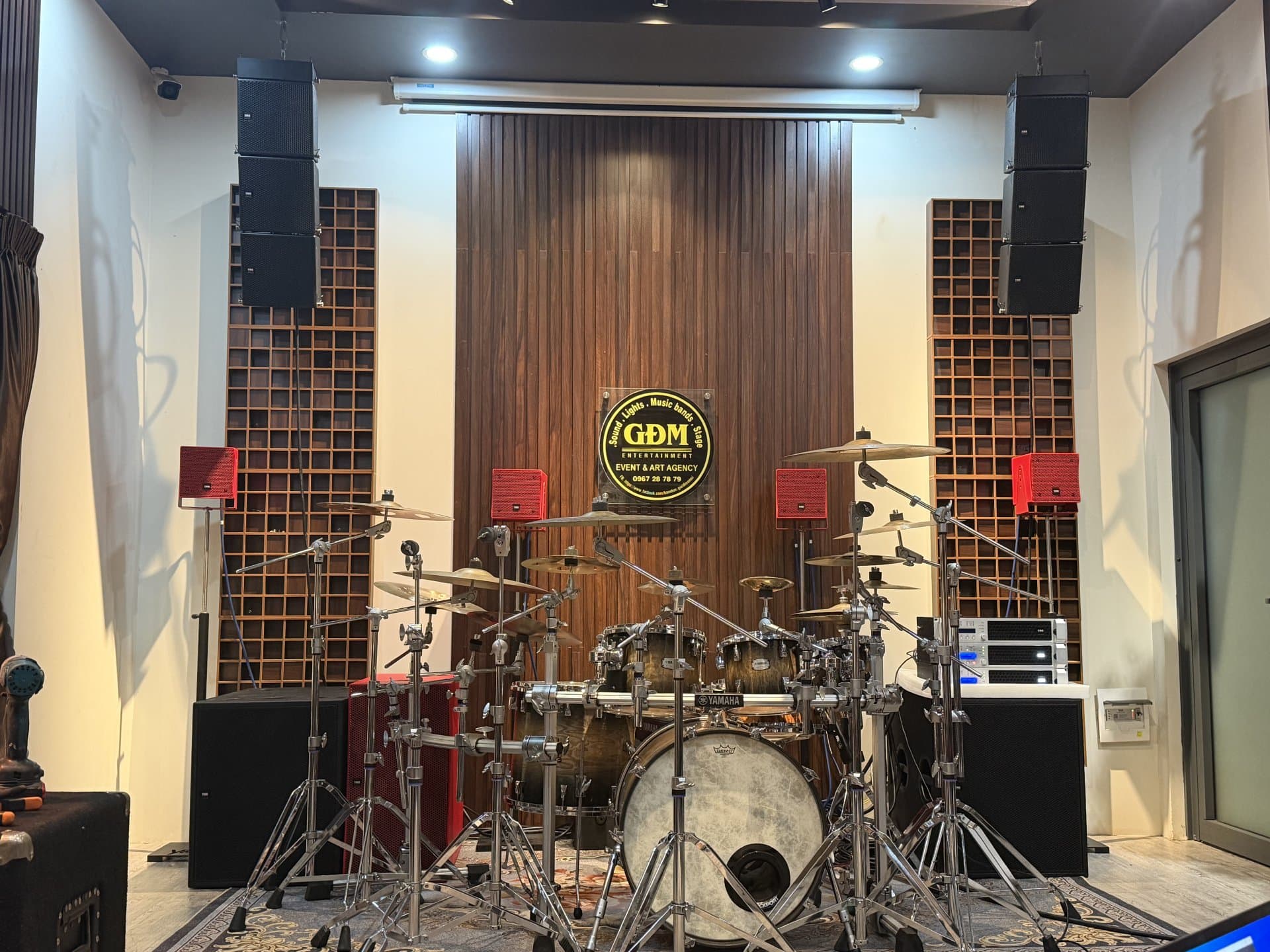 Cặp loa Line Array YME Nano Pro treo trần phía trên và loa YME CS 7P màu đỏ đặt phía dưới, cân chỉnh cho phòng nghe nhạc kiêm phòng trống tại nhà riêng.