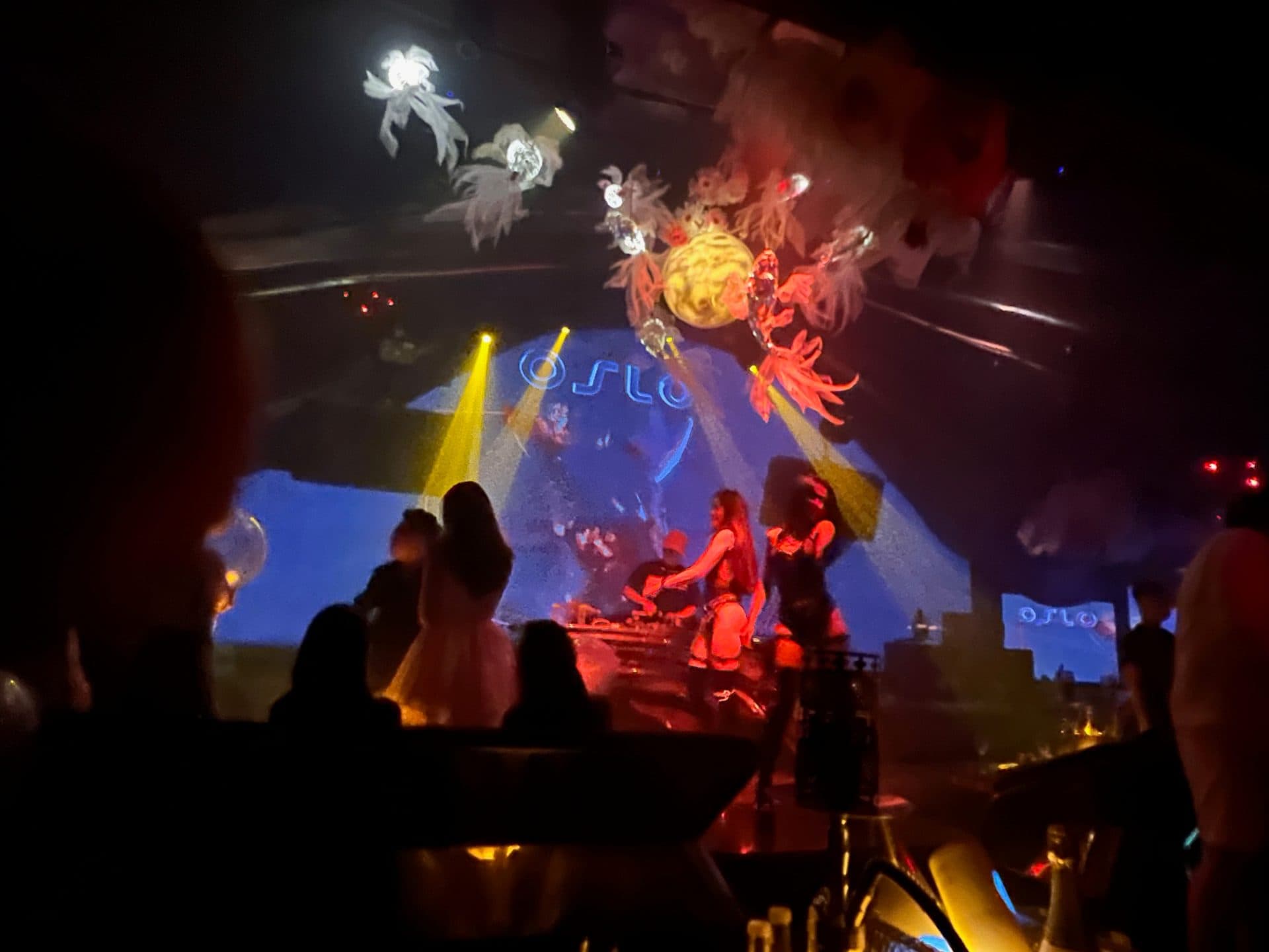 Sân khấu Oslo Club Quận 1 với màn LED hiển thị logo OSLO, vũ công và DJ, nhìn từ khu vực bàn khách.