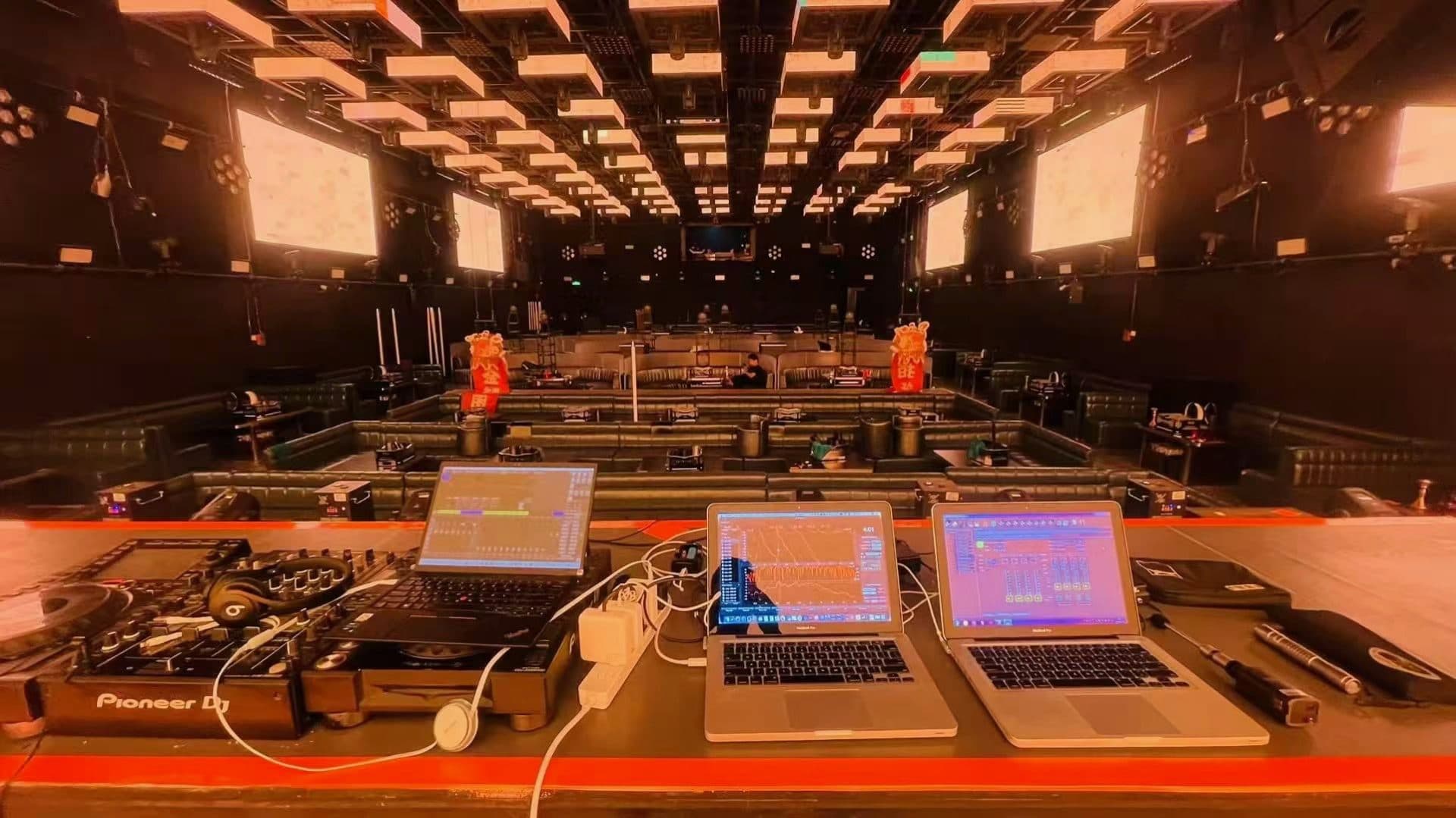 Góc nhìn từ bàn điều khiển với màn hình đo đạc Smaart và Pioneer DJ, nhìn ra không gian club nhiều tầng ghế VIP.
