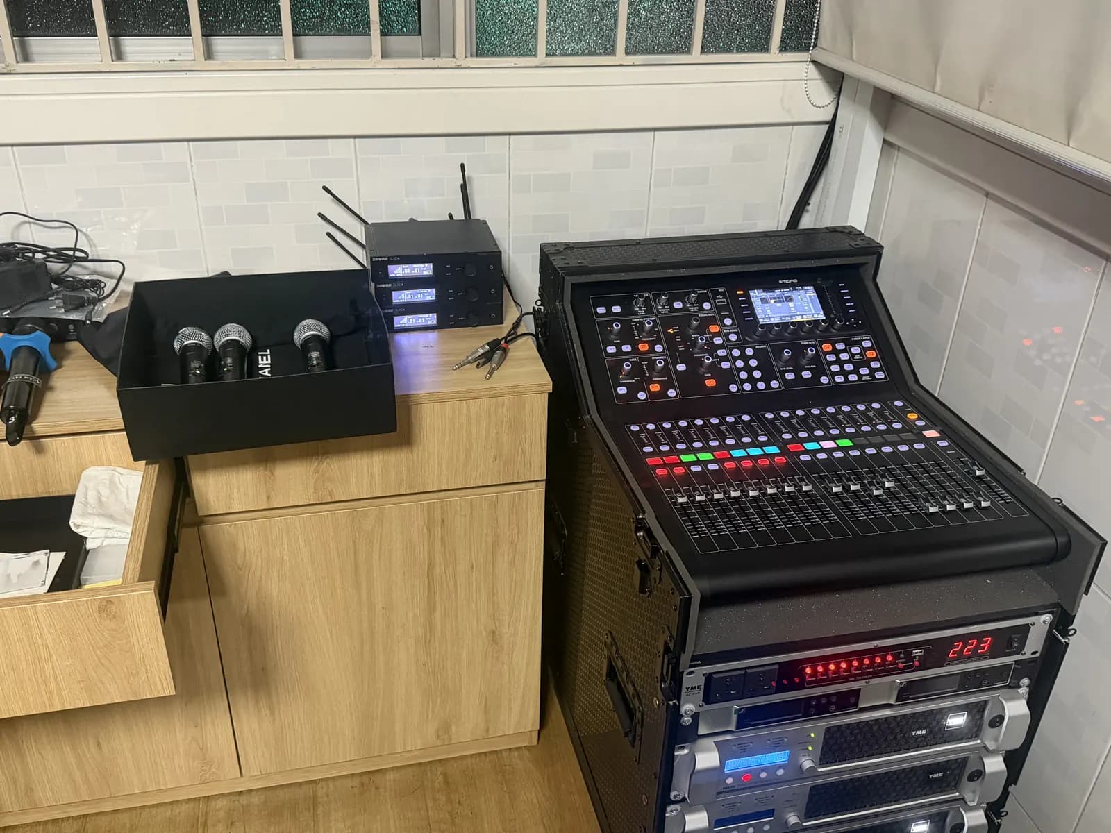 Rack thiết bị hoàn chỉnh gồm bàn mixer, bộ thu không dây và các tầng ampli công suất đặt sát tường.
