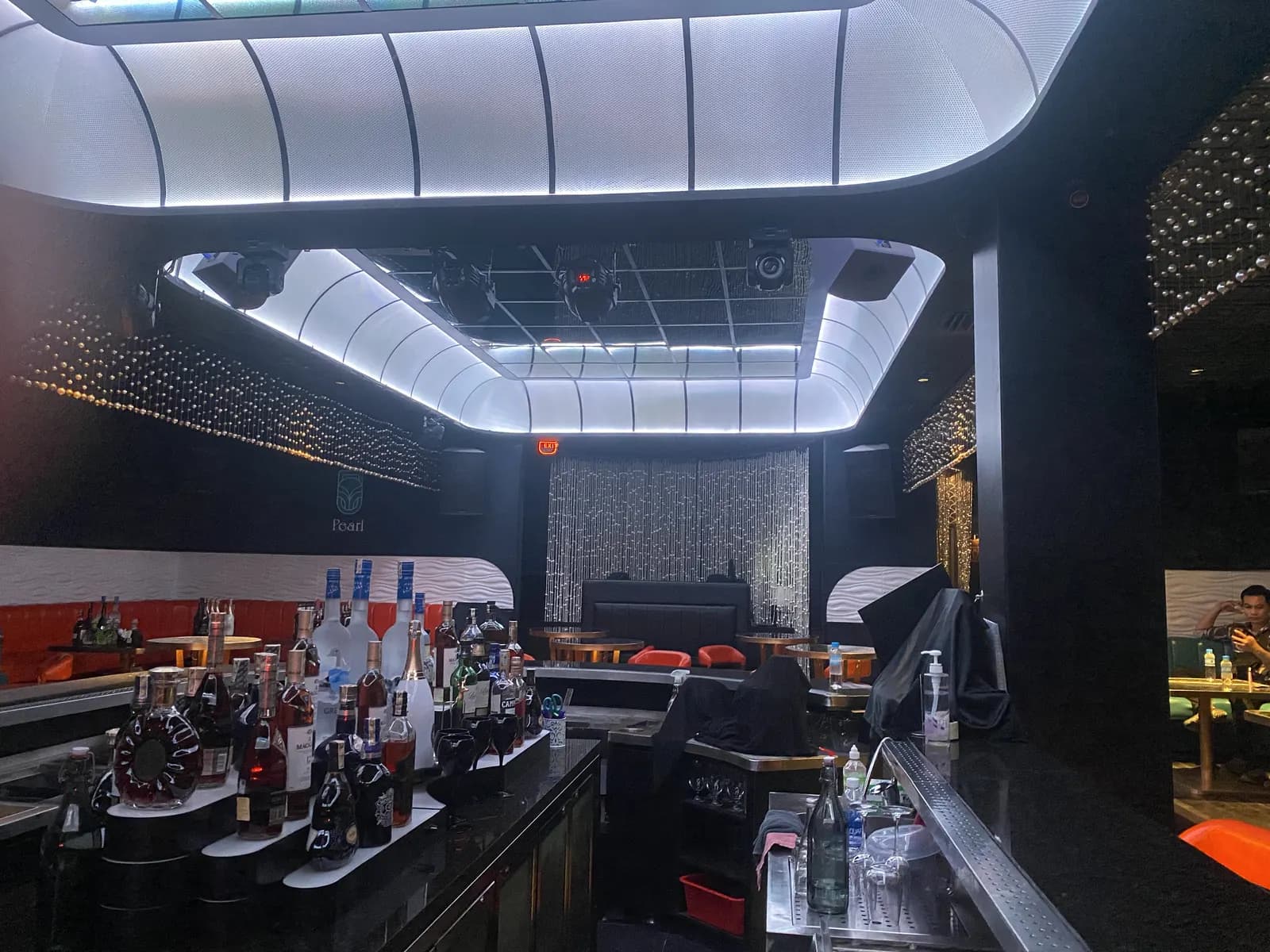 Nội thất quầy bar Natrix với trần gương cong, rèm hạt kim loại và các loa lắp tường quanh khu ngồi.